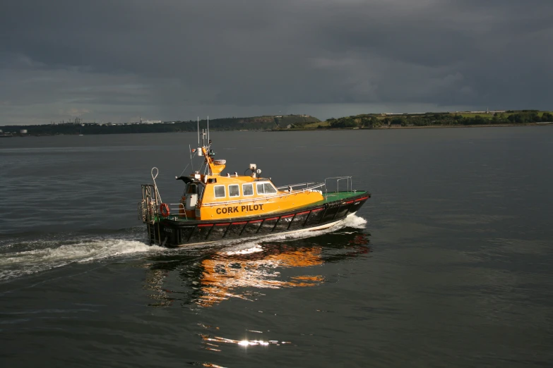 a yellow and black tugboat on water under cloudy skies