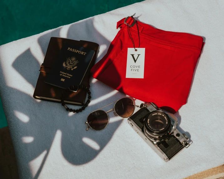 sunglasses, sunglasses, book and passport laying on a bed