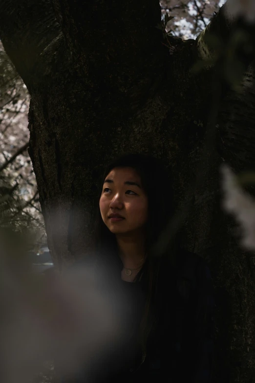 a woman is standing under the tree in the dark