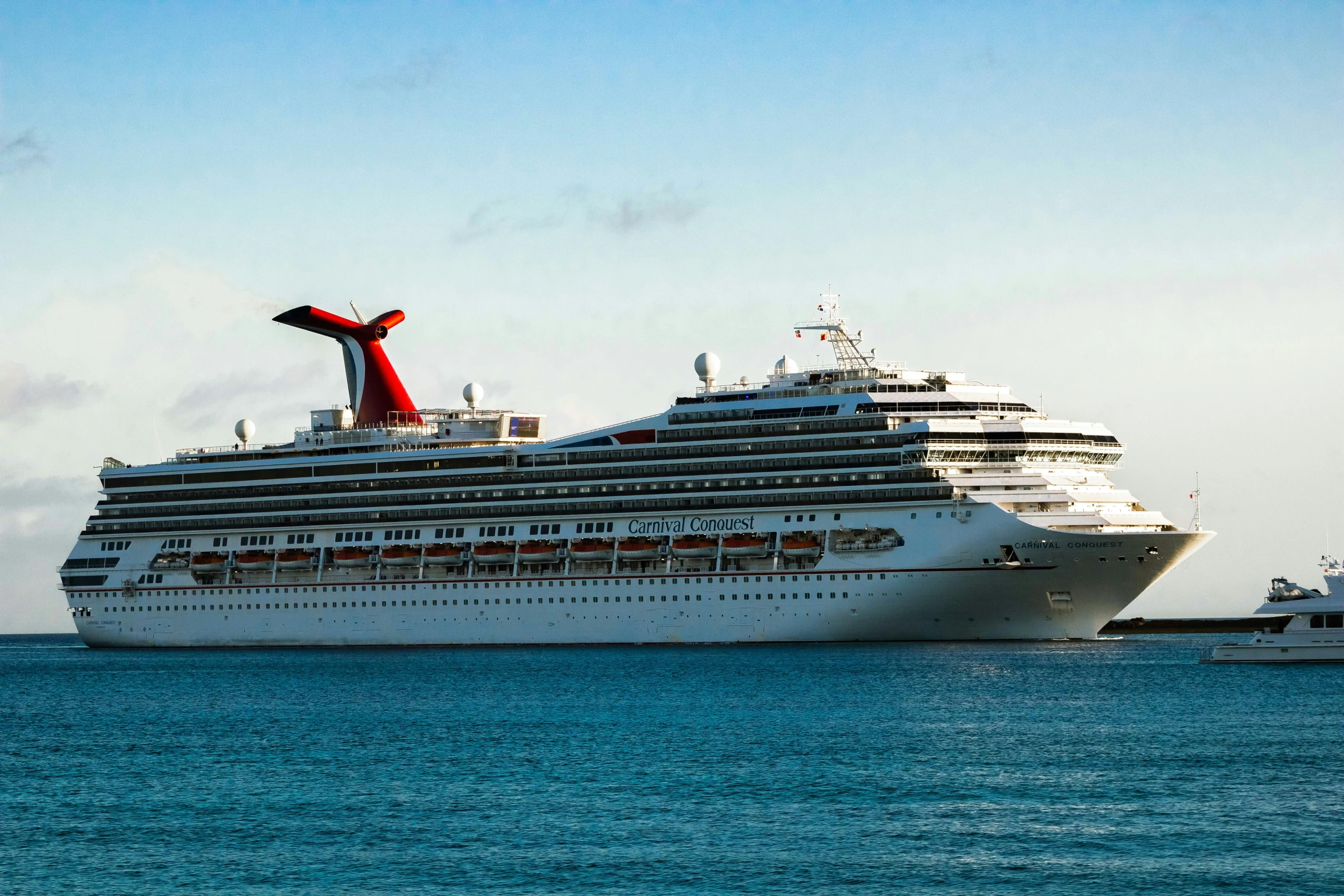 the cruise ship is docked near a smaller boat