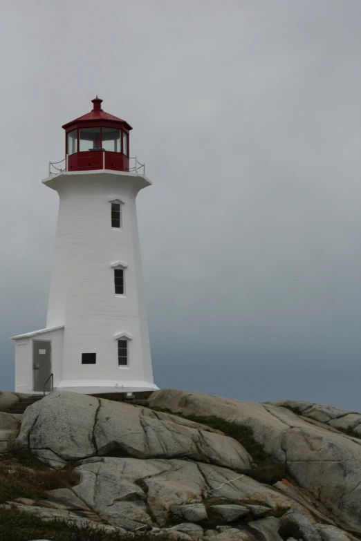 a lighthouse on top of a rock in the middle of a cloudy sky