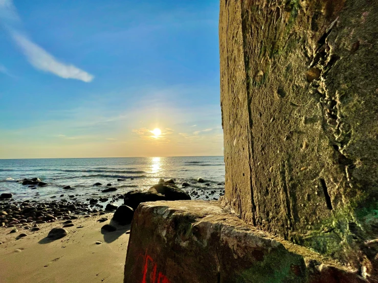 sun shining on the beach next to rocks and water