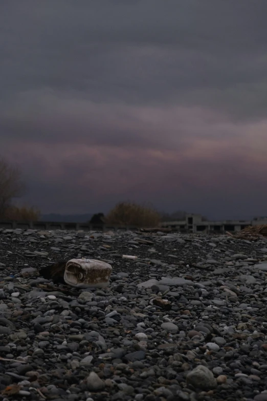 rocks and gravel are arranged at the base of a bench under a cloudy sky