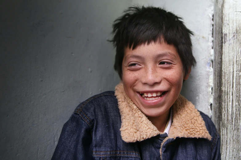 a close - up po of a boy smiling while wearing a jacket