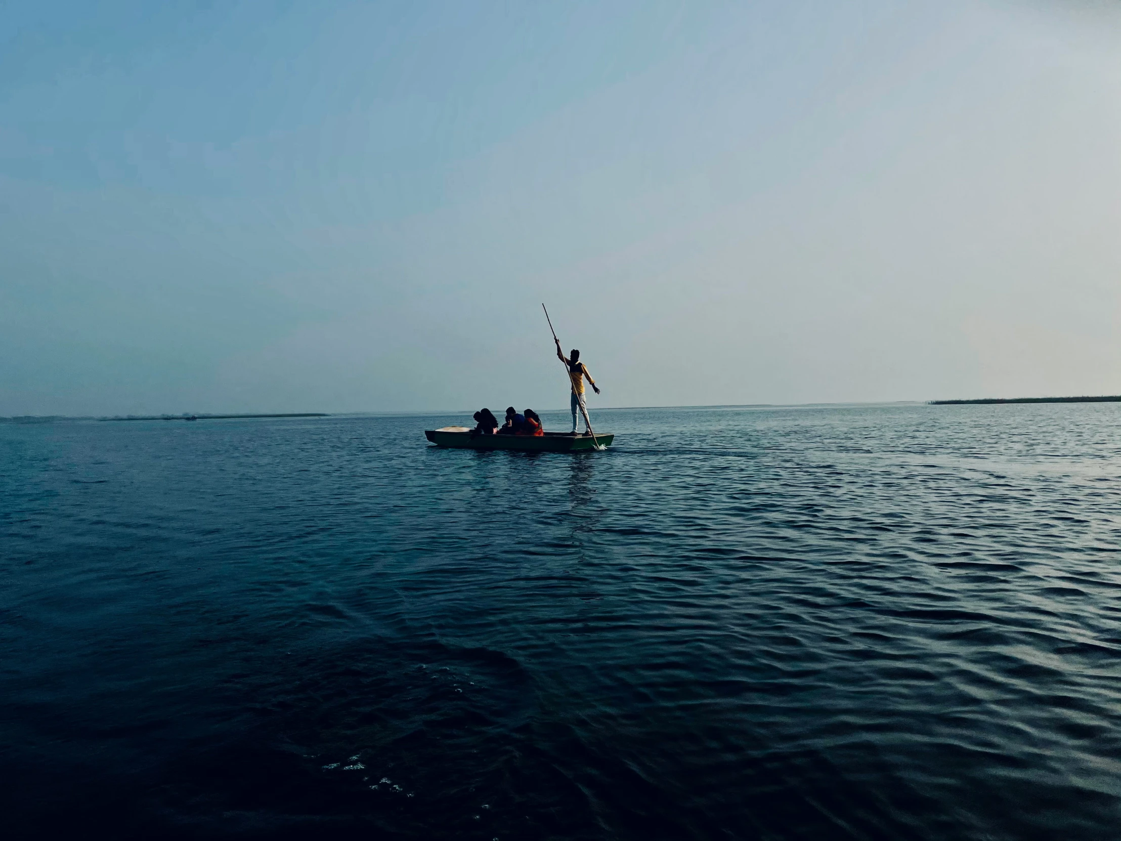 people riding in a small boat with a flag on top of the water