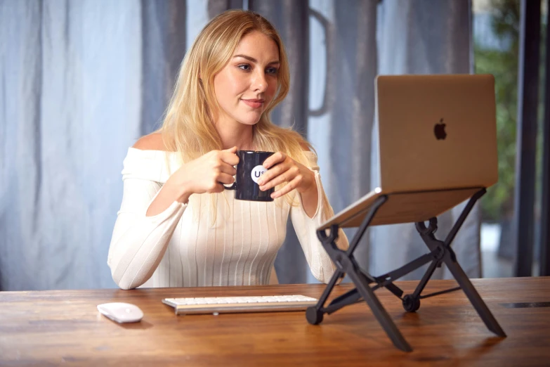 the woman is holding her cup as she looks at her laptop