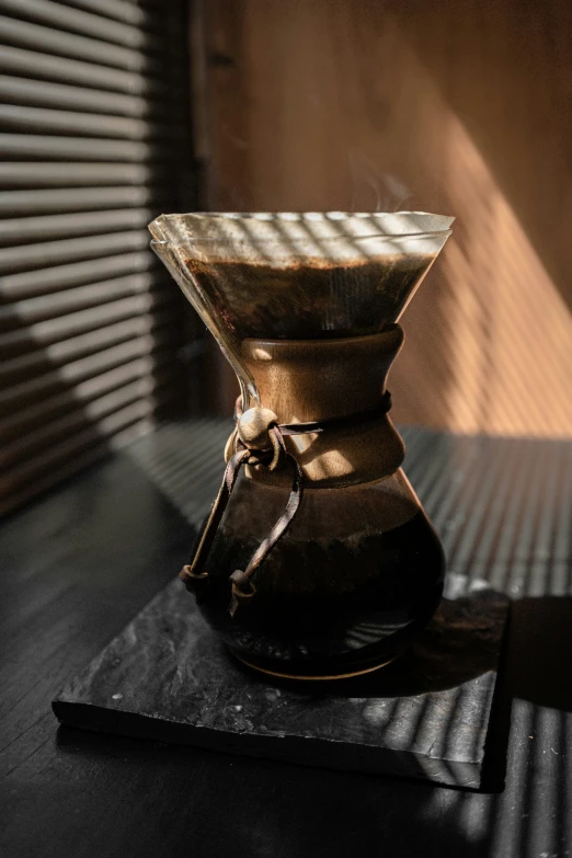 a brown coffee maker on black table in room