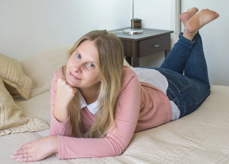 a woman lying on a bed with her hand under her chin