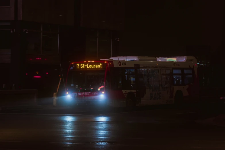 a dark street has a bus turning and has it headlights on