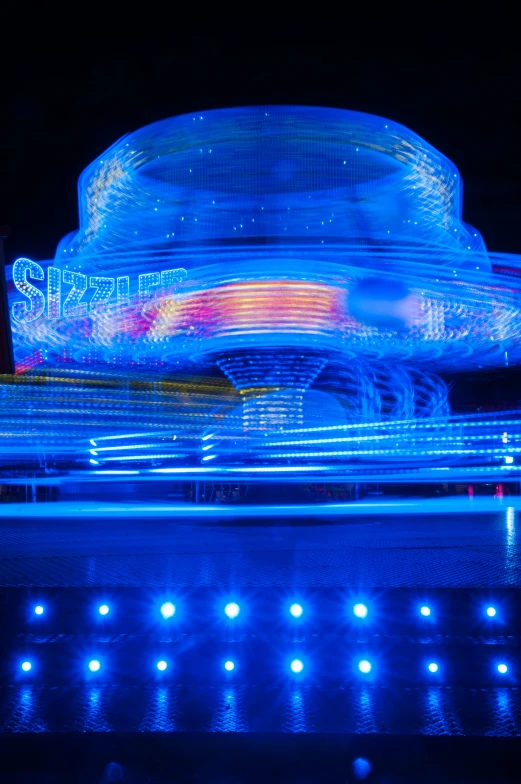 an illuminated carnival ride at night with a colorful light show