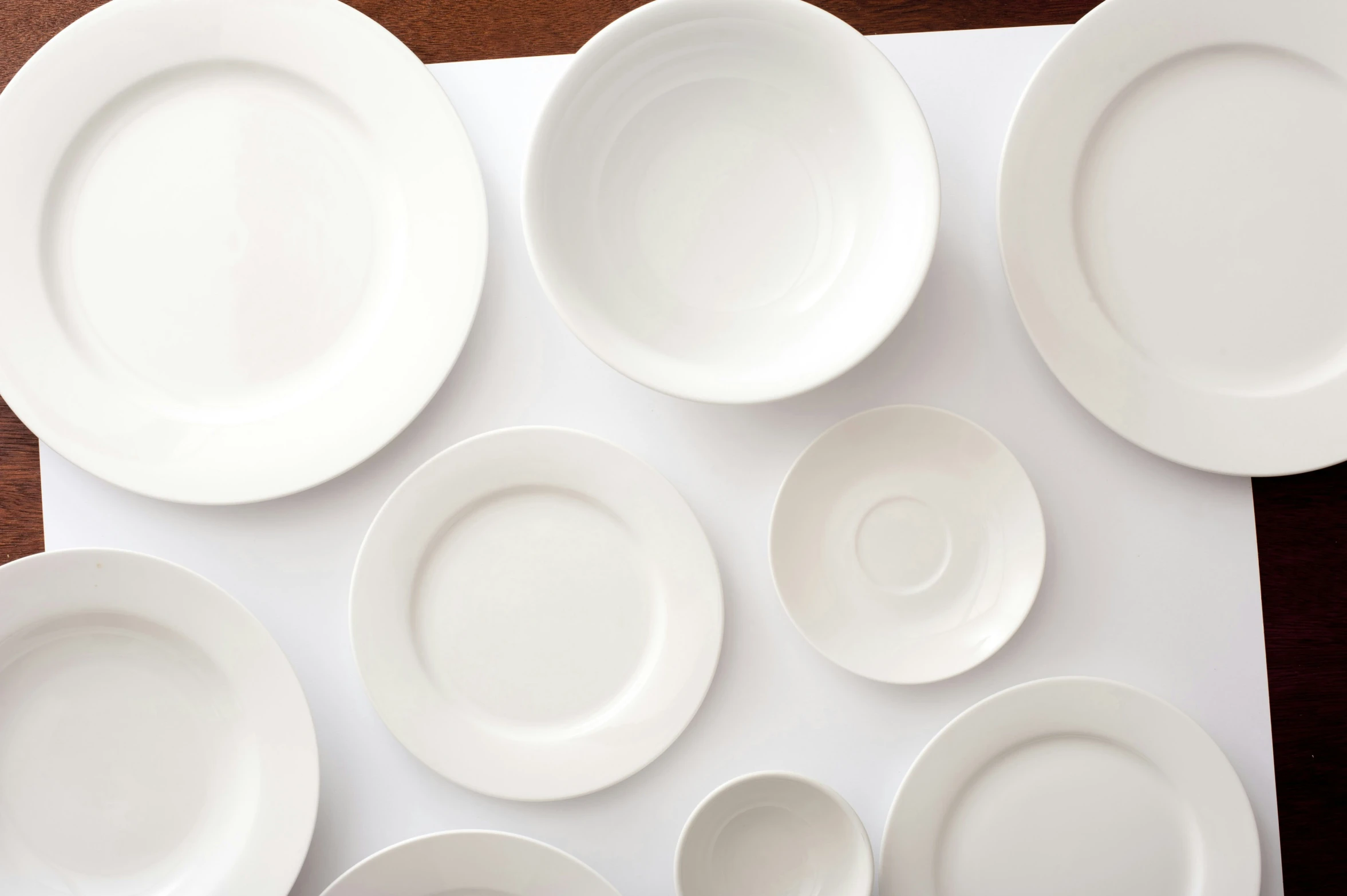 table setting with white china dishes laid out on top of a place mat