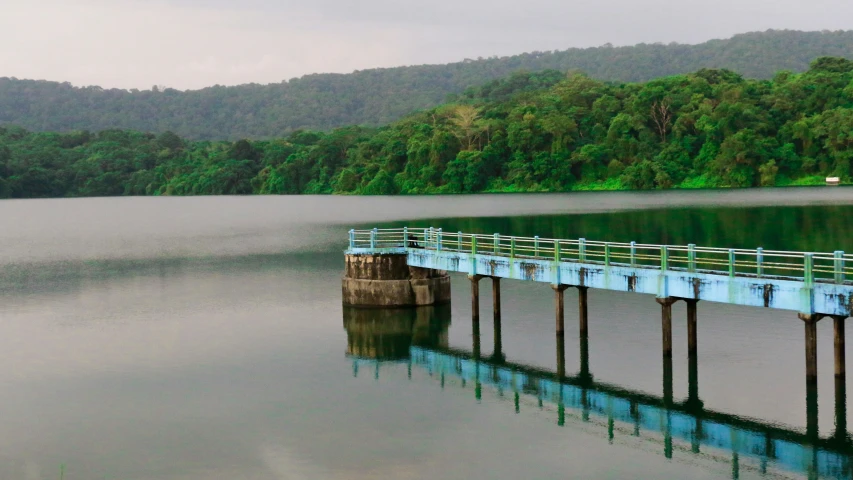 the pier is empty on the water with trees in the background