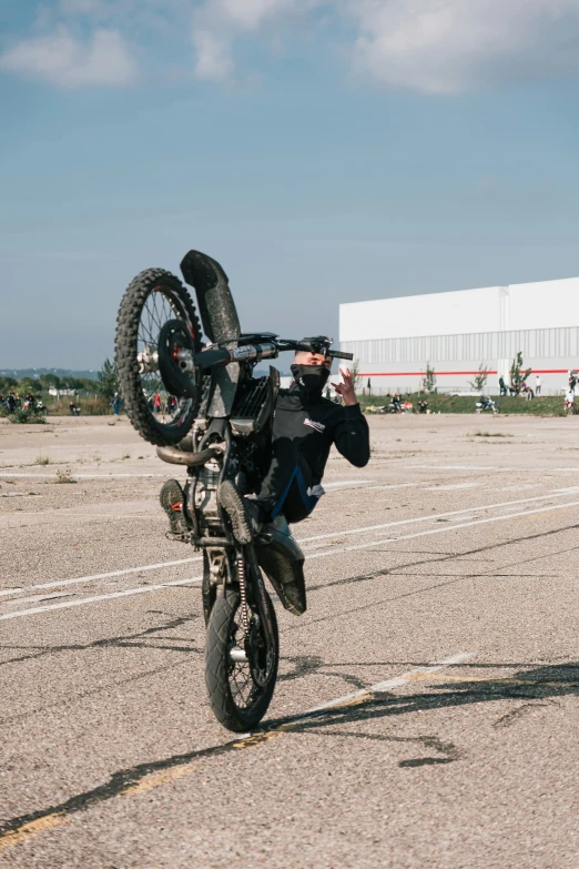 a motorcycle rider performing a wheelie on a paved surface