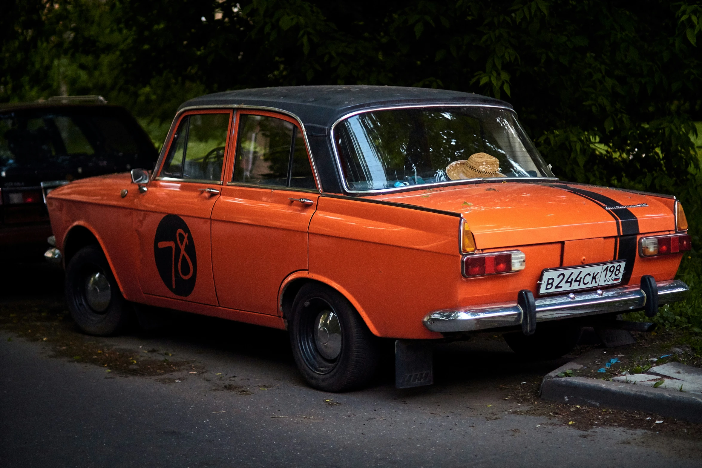 an orange car with a teddy bear sitting in the hood