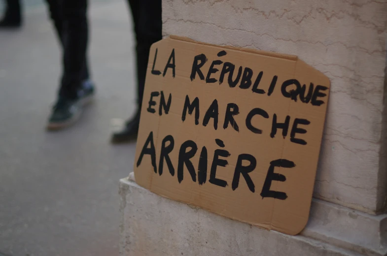 a protest sign in french on a concrete pillar