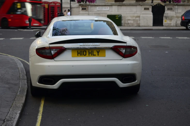 a car parked on a city street with a red bus behind it