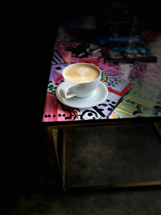 a coffee cup with a white saucer on it on a multicolored table