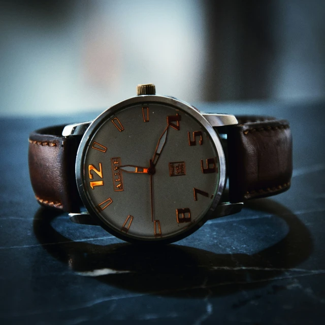 the watch has a large round face and a brown leather strap