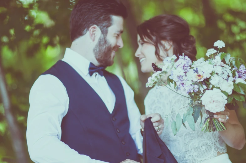 the bride and groom are standing in the woods