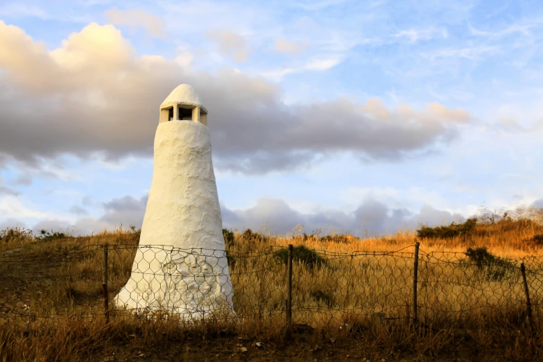 a large white building sitting in the middle of a dry grass field