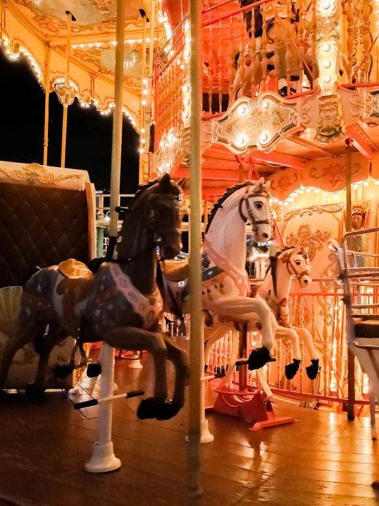 three carousel horses standing on the ground at night