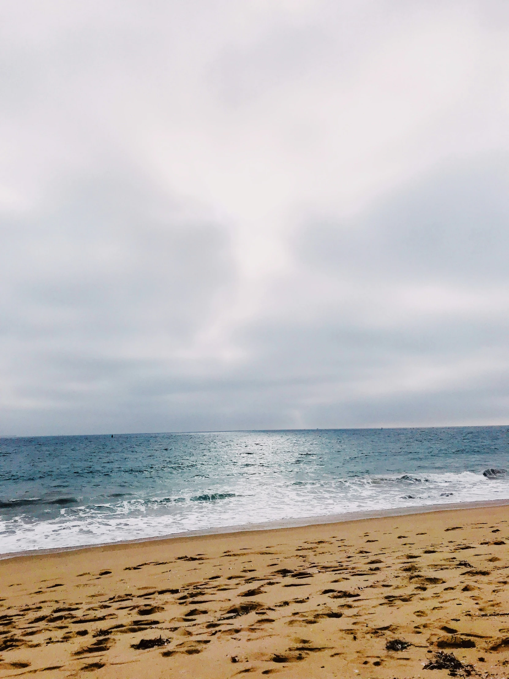 a surfer walks out into the ocean from a beach