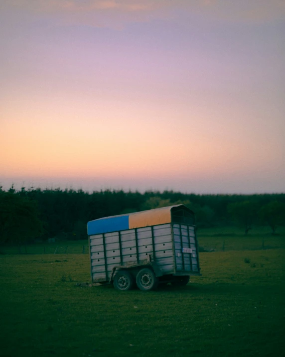 an open field has a trailer that is filled with hay