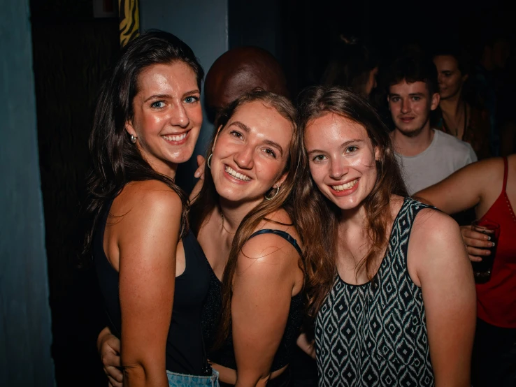 three women smiling for the camera at night