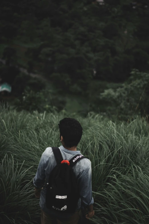 a man is wearing a backpack as he walks through the grass