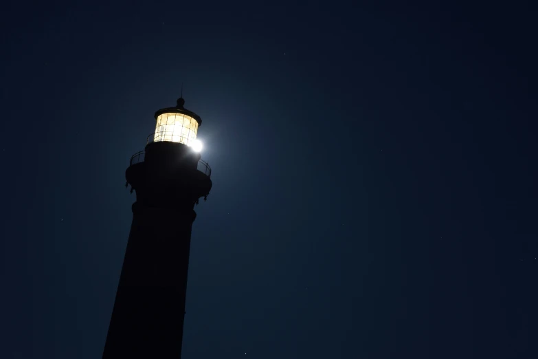 a black lighthouse at night in the ocean