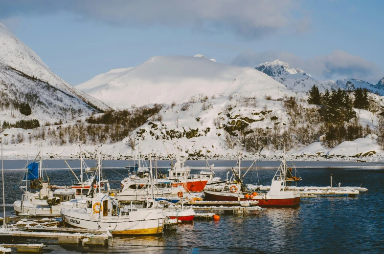 a couple boats sitting docked in front of a mountain