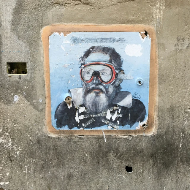 a man with a beard and red glasses on a cement wall