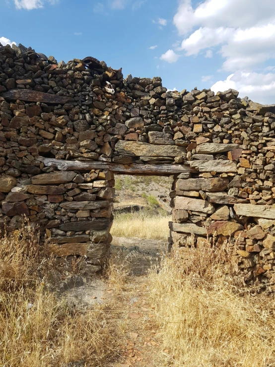 a very old brick building with some dried grass