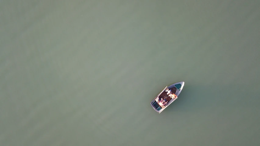 a lone boat floats away in a green body of water