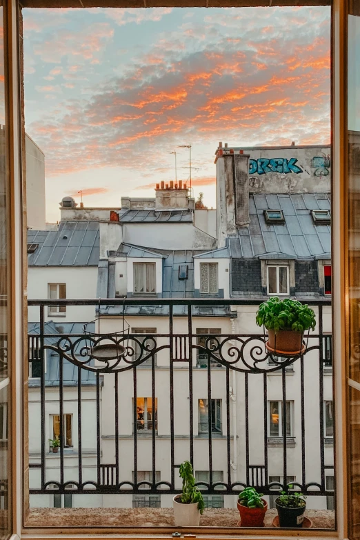 some buildings and a balcony are seen through a window