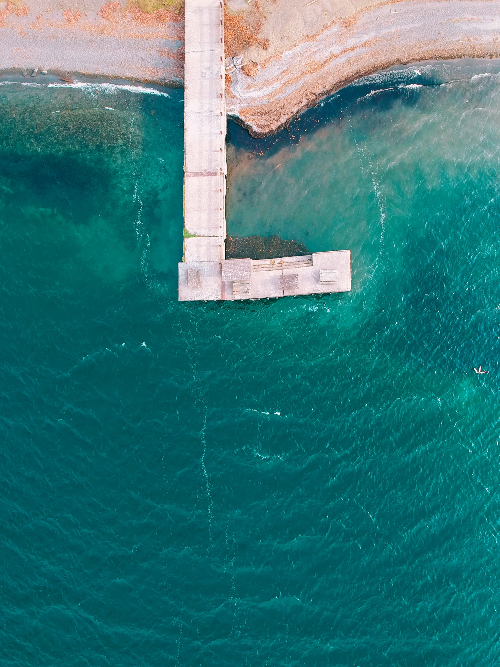 a bird's eye view of a body of water and a pier that has an opening at the end