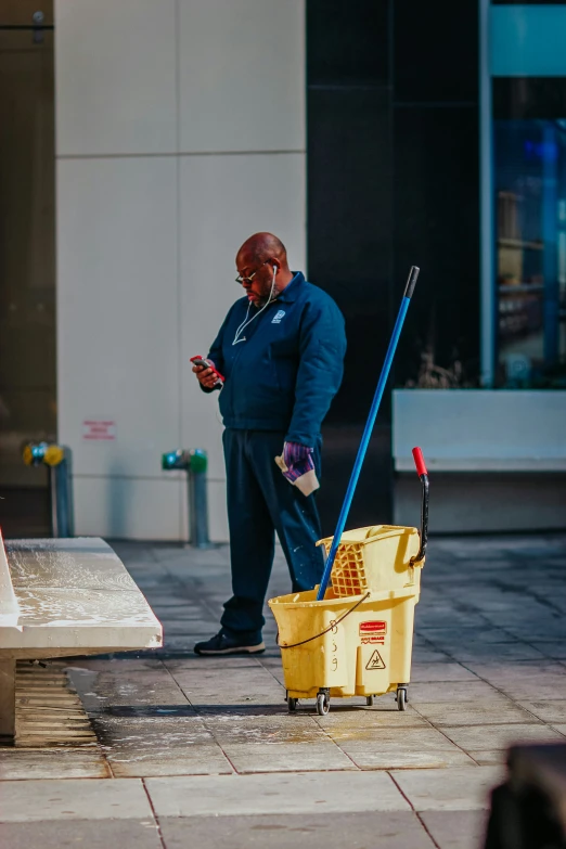 a man standing on the street with two mop heads