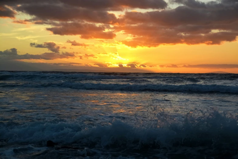 a beach scene with a sunset and dark clouds