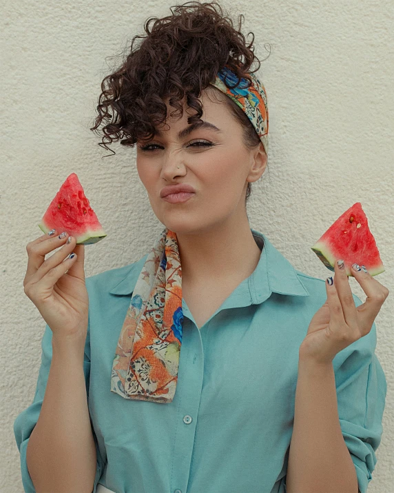 the woman has two pieces of watermelon on her fingers