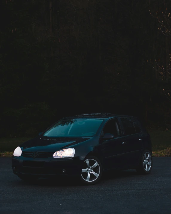 an automobile sits in a parking lot next to a wooded area