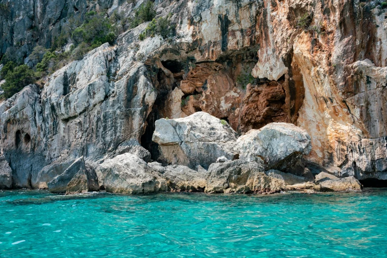 a rock cliff is next to a body of water