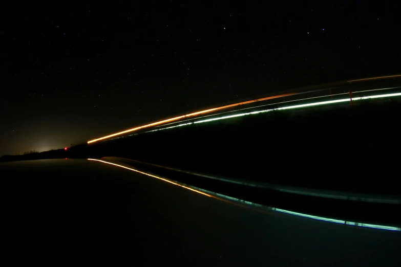 the time lapse image of a road in front of a night sky