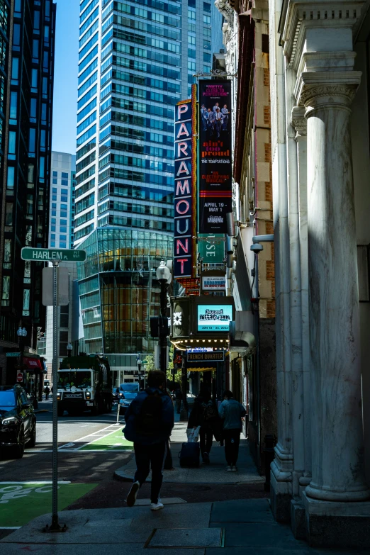 people walk down a sidewalk near a tall building in a city