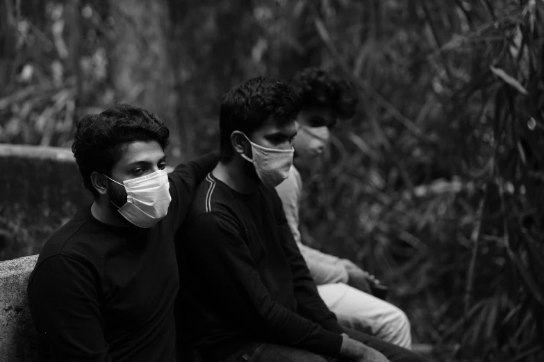 two people wearing face masks sitting on a bench