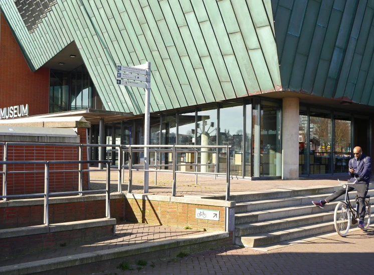 a person riding a bike past stairs and a building