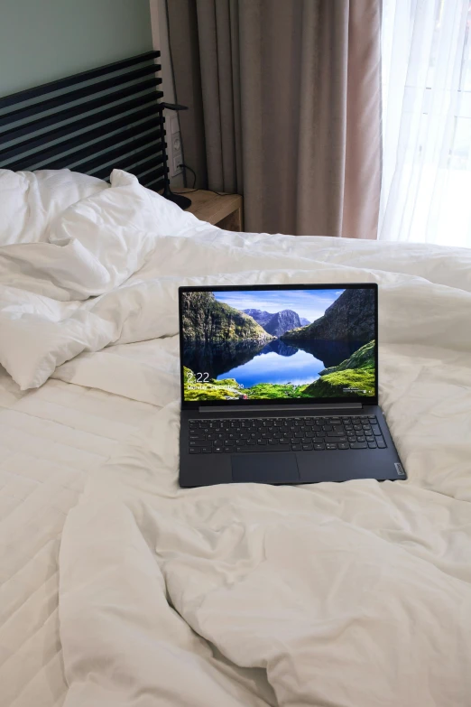 a laptop sitting on a bed with a white comforter