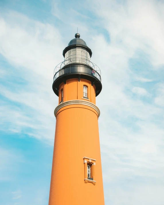 a tall orange light house with a black top