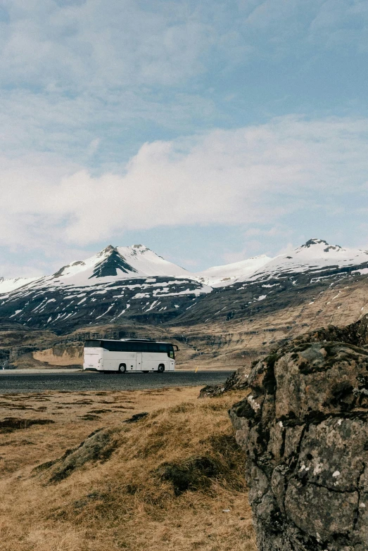 there is a white bus driving through the hills