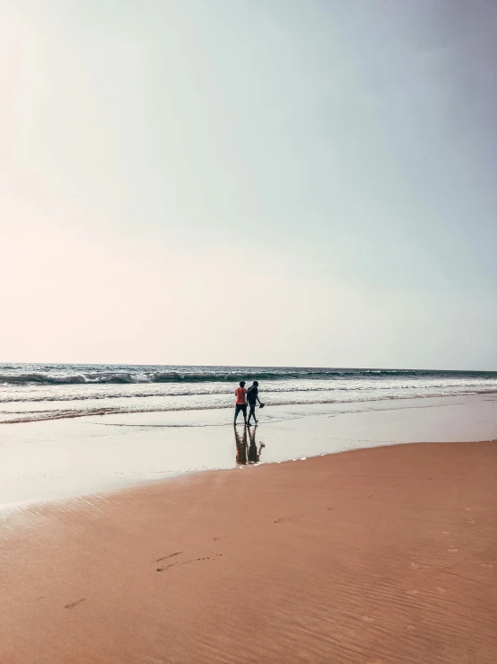 two people standing on the beach with surfboards