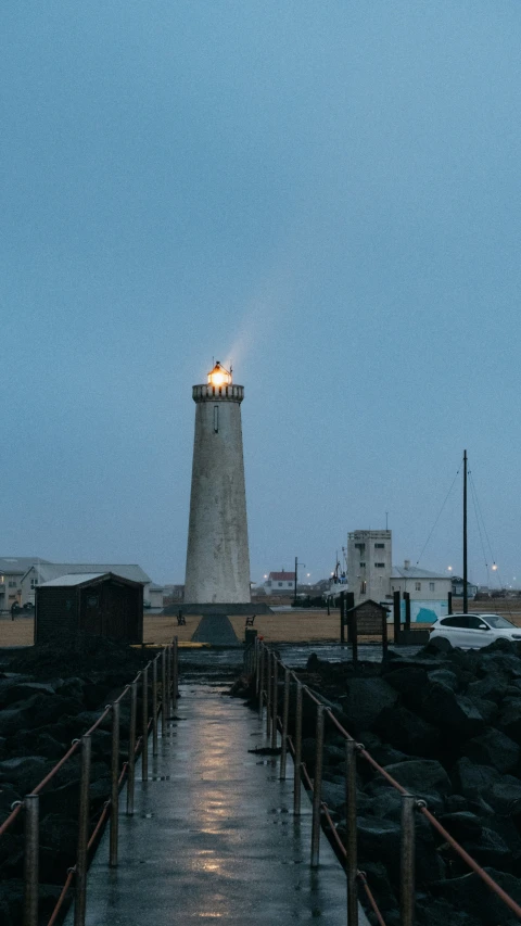 lighthouse on top of an industrial port with a long walkway leading up to it